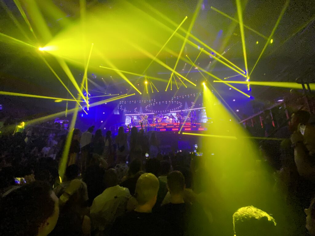 Crowd at a nightclub concert with yellow laser beams over the stage