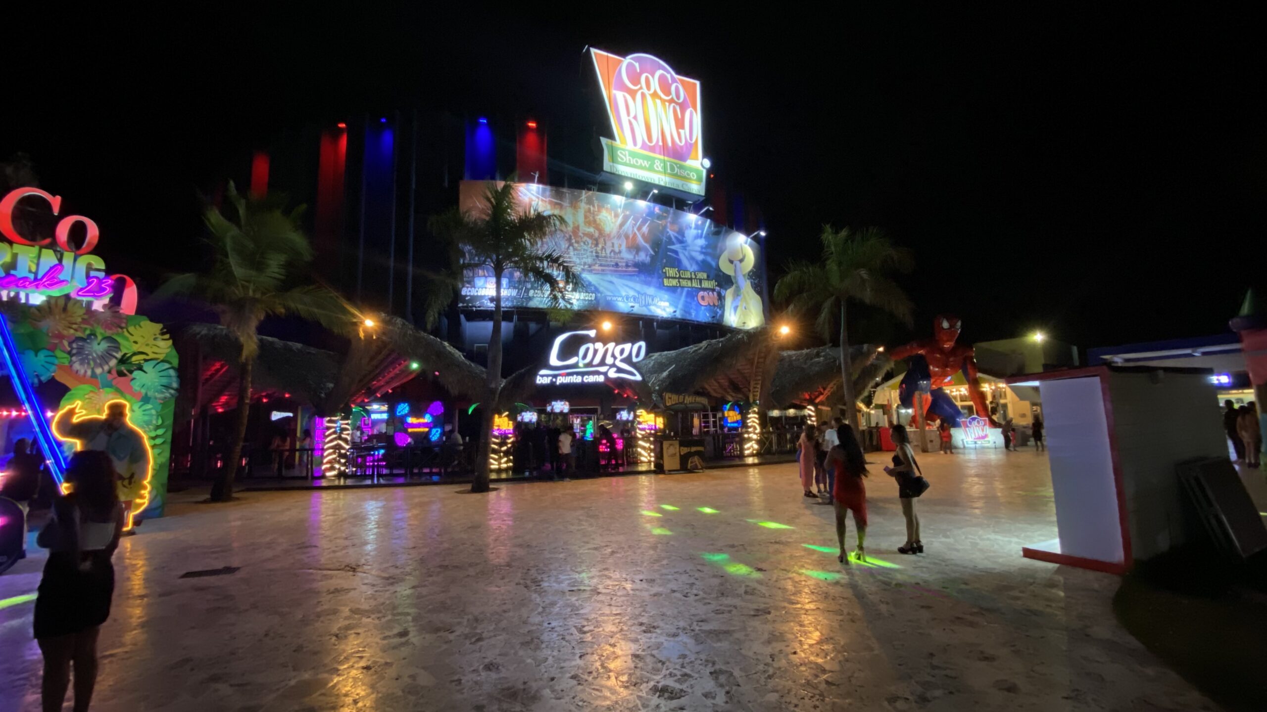 Coco Bongo nightlife plaza lit up with neon signs and tourists walking at night