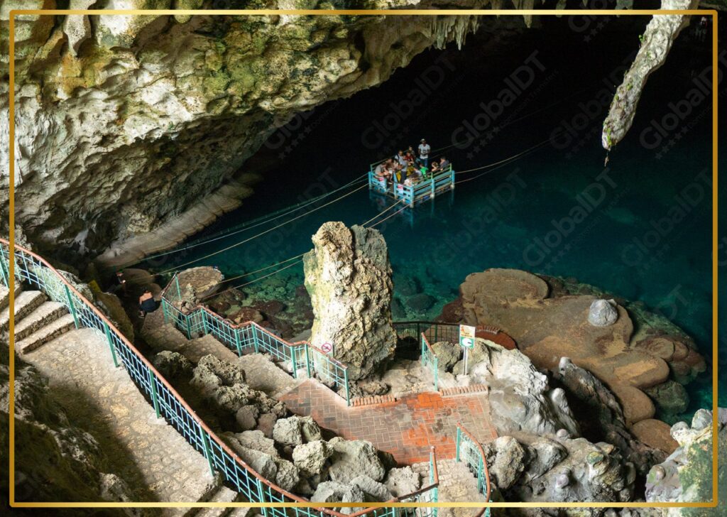 Turistas en una balsa dentro de la cueva Los Tres Ojos con agua turquesa y pasarelas