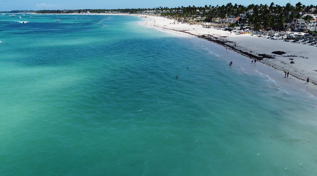 Vista aérea de Playa Bávaro con agua turquesa, bañistas y resorts en la orilla