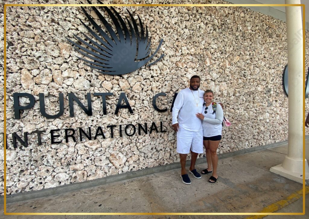 Couple posing in front of the Punta Cana International Airport coral stone welcome sign