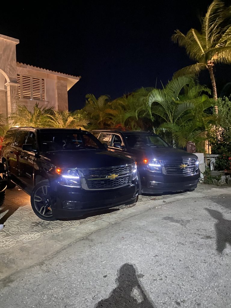 Two black Chevrolet Suburbans parked at a villa at night in Punta Cana