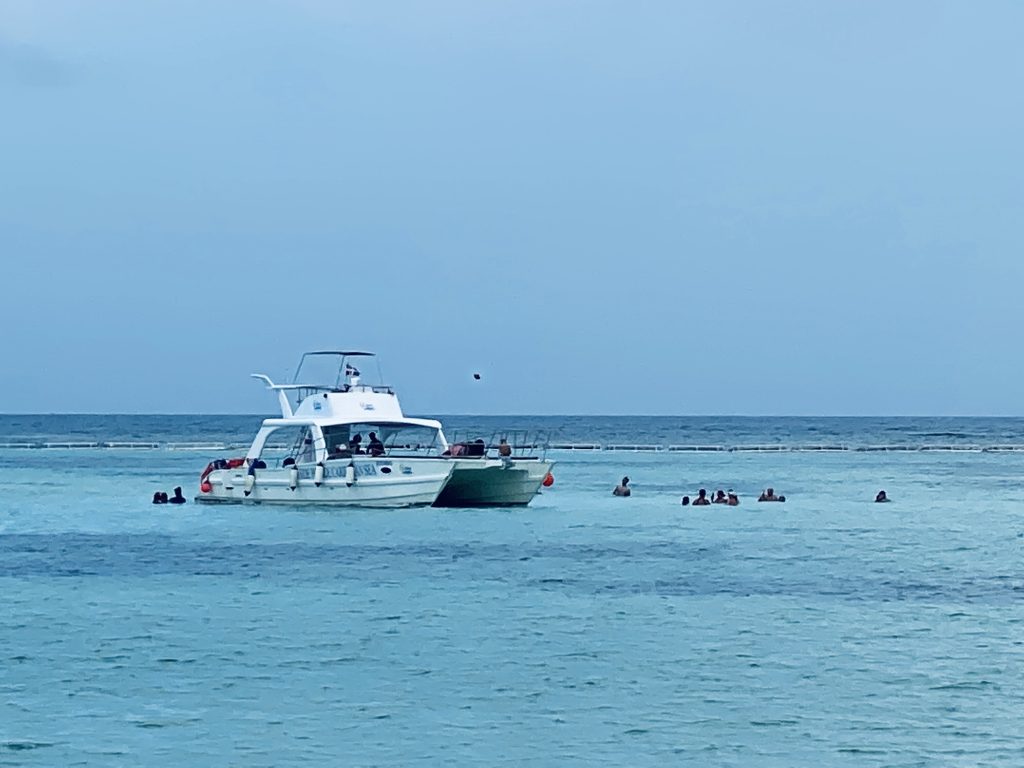 Barcos y personas haciendo snorkel al atardecer frente a la costa de La Romana