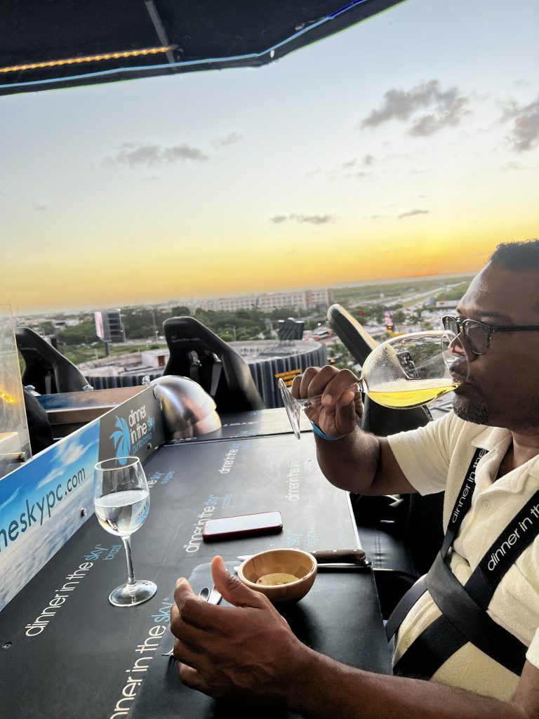 Hombre tomando una bebida durante una cena al atardecer en un restaurante en las alturas