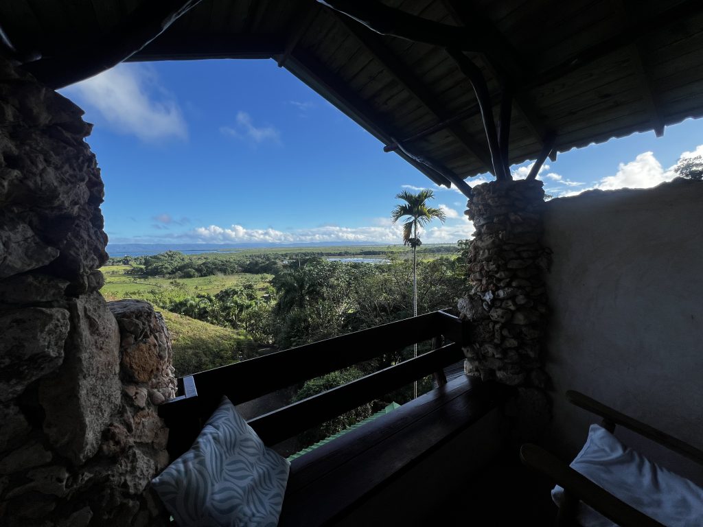 Terraza techada con vista a colinas tropicales, palmeras y la costa a lo lejos