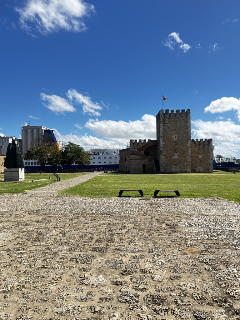 Torre de piedra y fortaleza Ozama con bandera bajo cielo azul en Santo Domingo