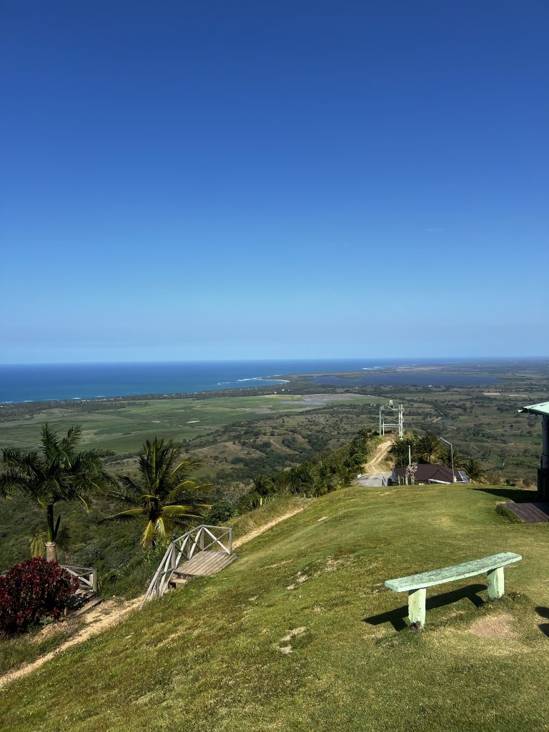 Vista panorámica desde la cima de Montaña Redonda sobre llanuras verdes y el mar