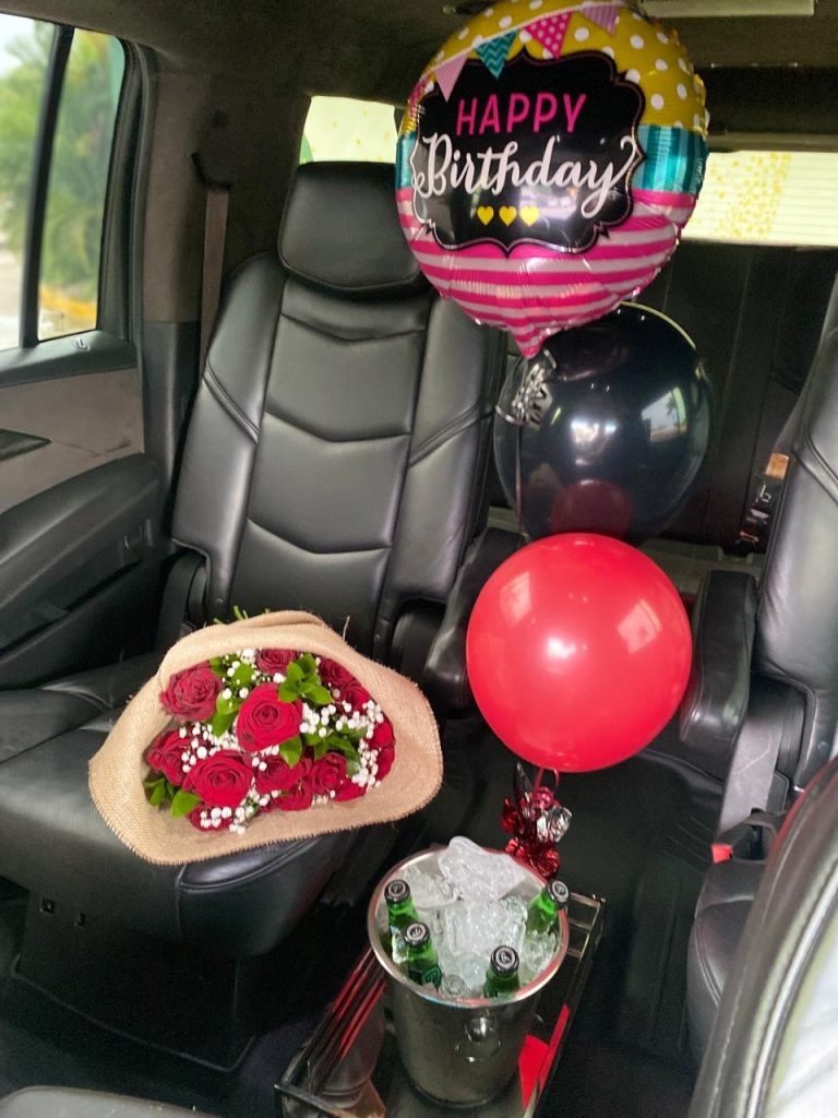 Cadillac Escalade interior with red rose bouquet, birthday balloons and champagne on ice
