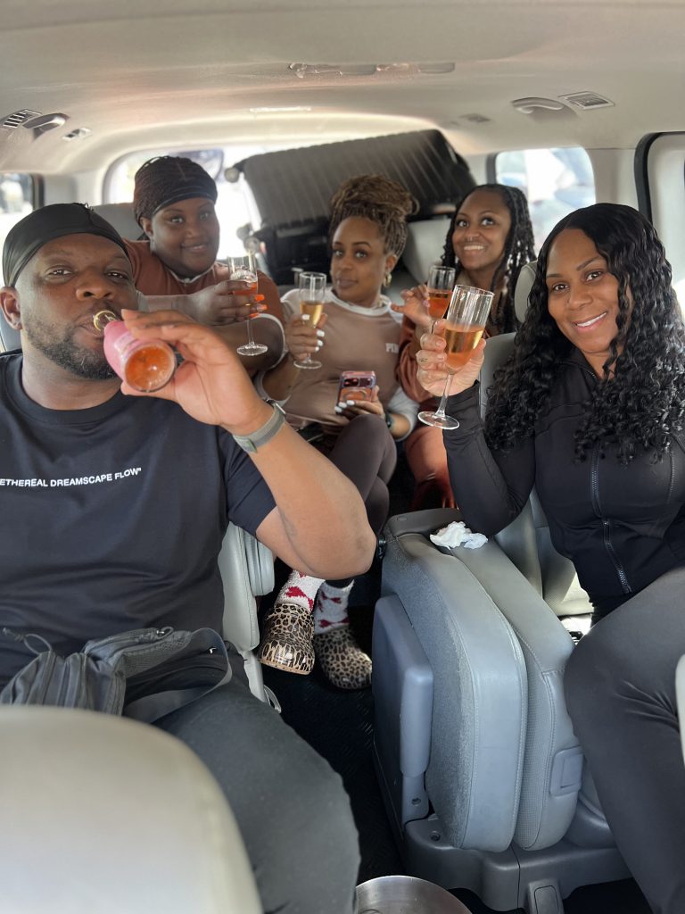 Five passengers toasting with sparkling wine inside a GlobalDT van during a transfer