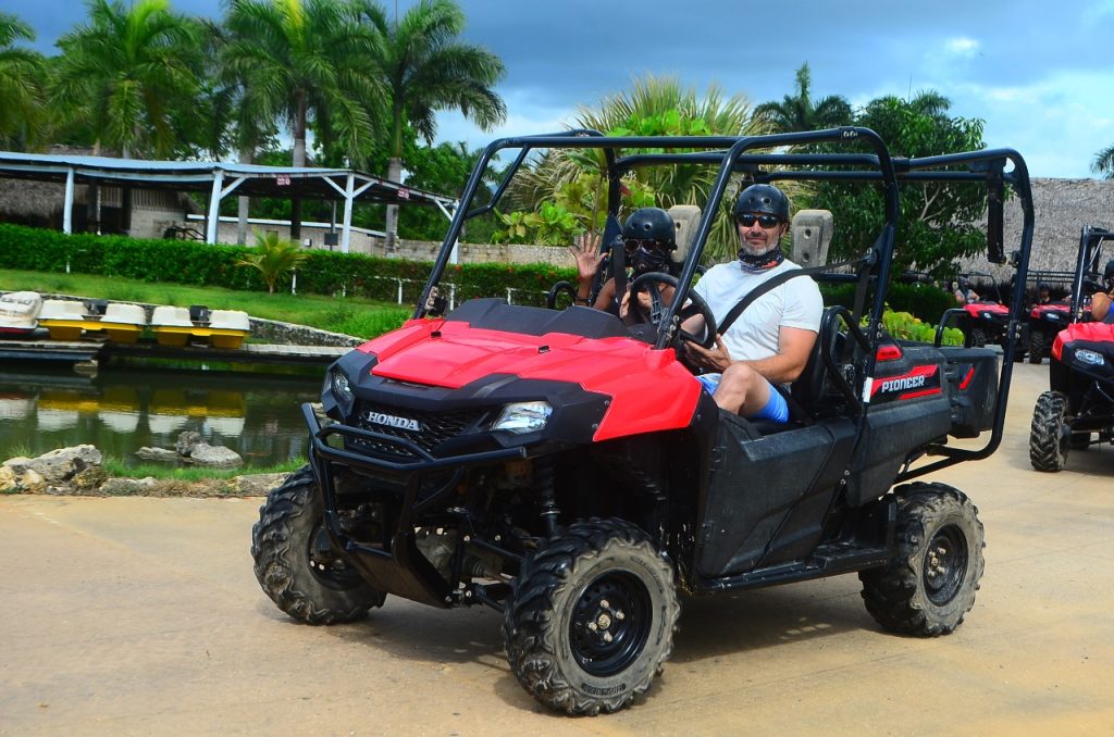 Dos personas recorren un sendero turístico tropical en un ATV Honda rojo lado a lado